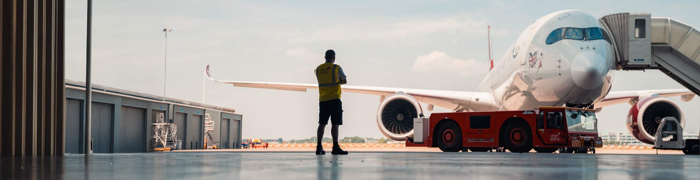 Aircraft engineer in hanger looking at a Virgin Atlantic plane