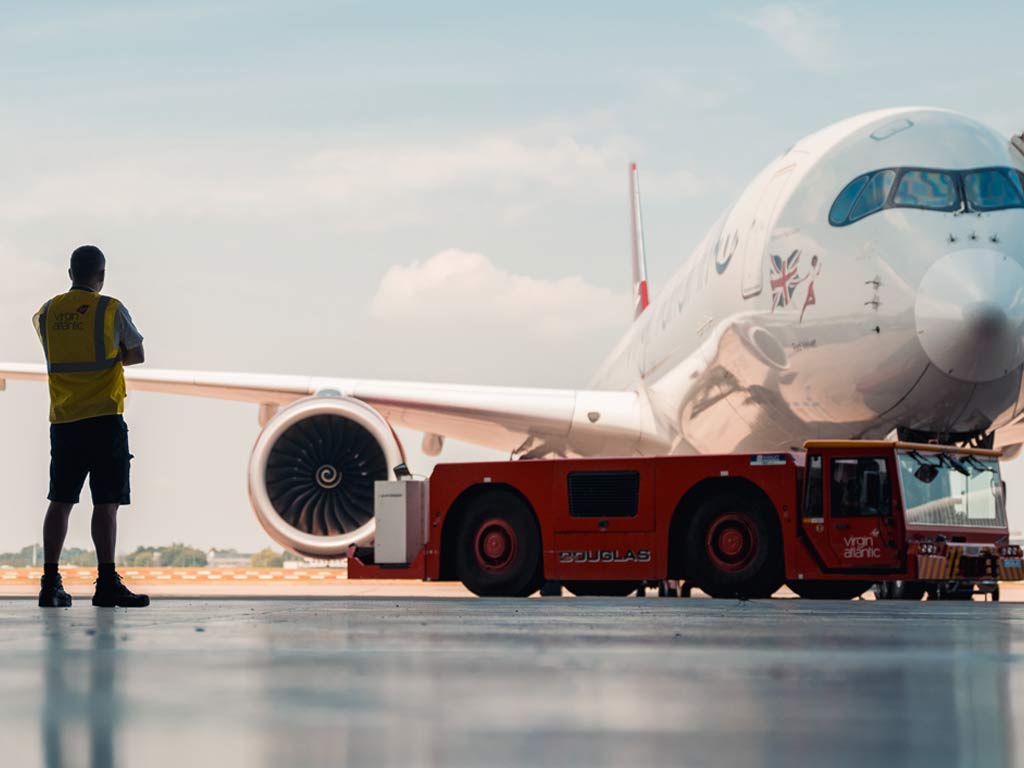 Aircraft engineer in hanger looking at a Virgin Atlantic plane