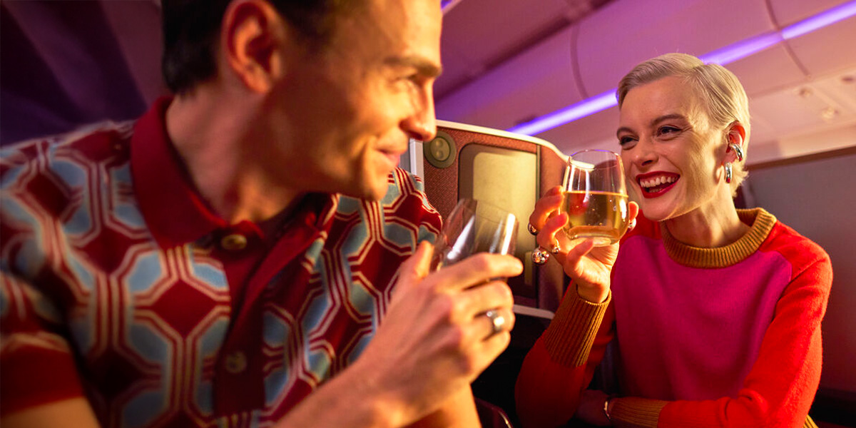 A man and a woman laugh whilst sharing a drink in an Upper Class Suite