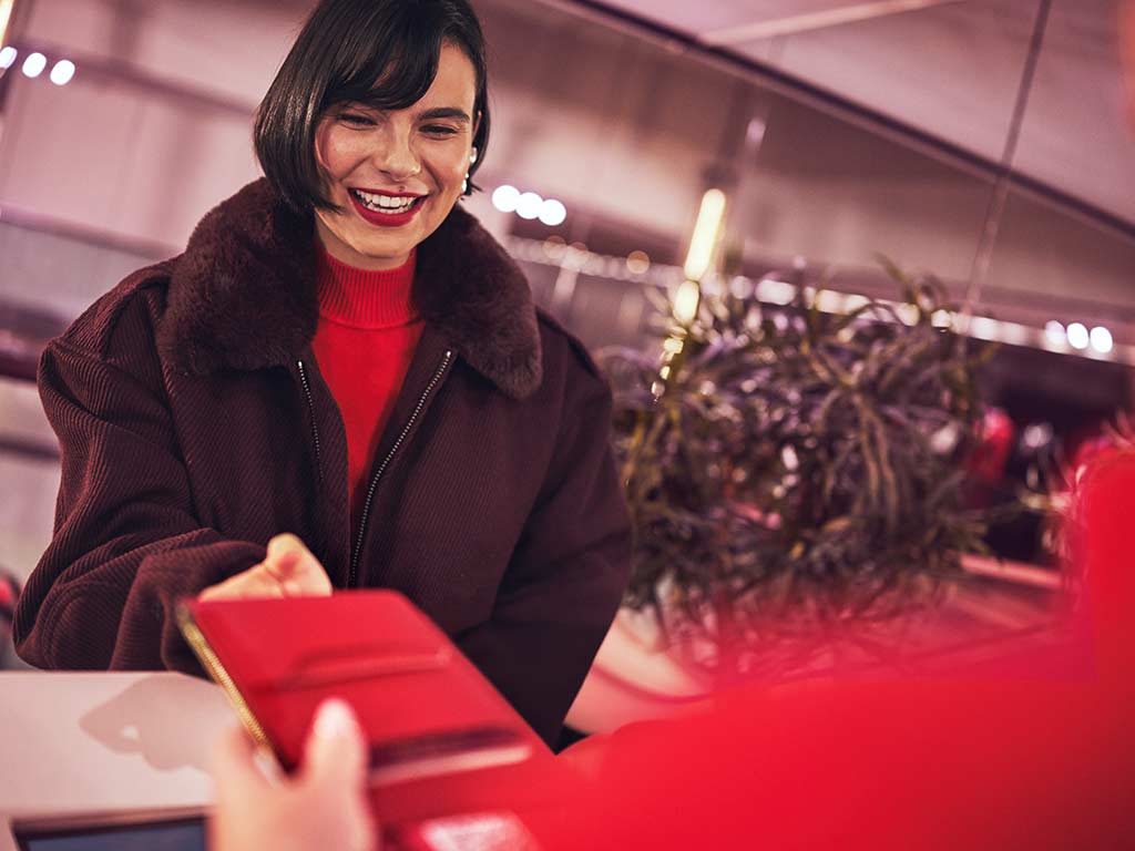 Lady checking in for her flight in a brown jacket