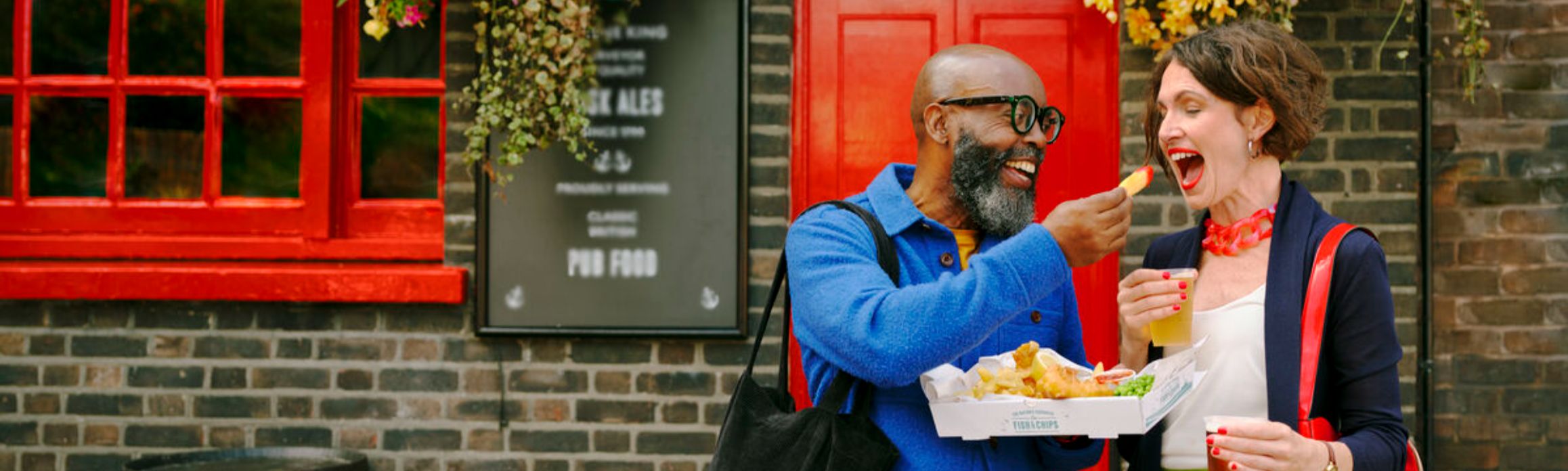 Couple eating fish and chips outside a pub