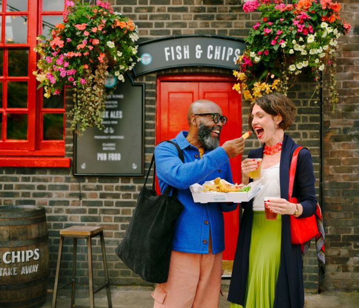 Couple eating fish and chips outside a pub