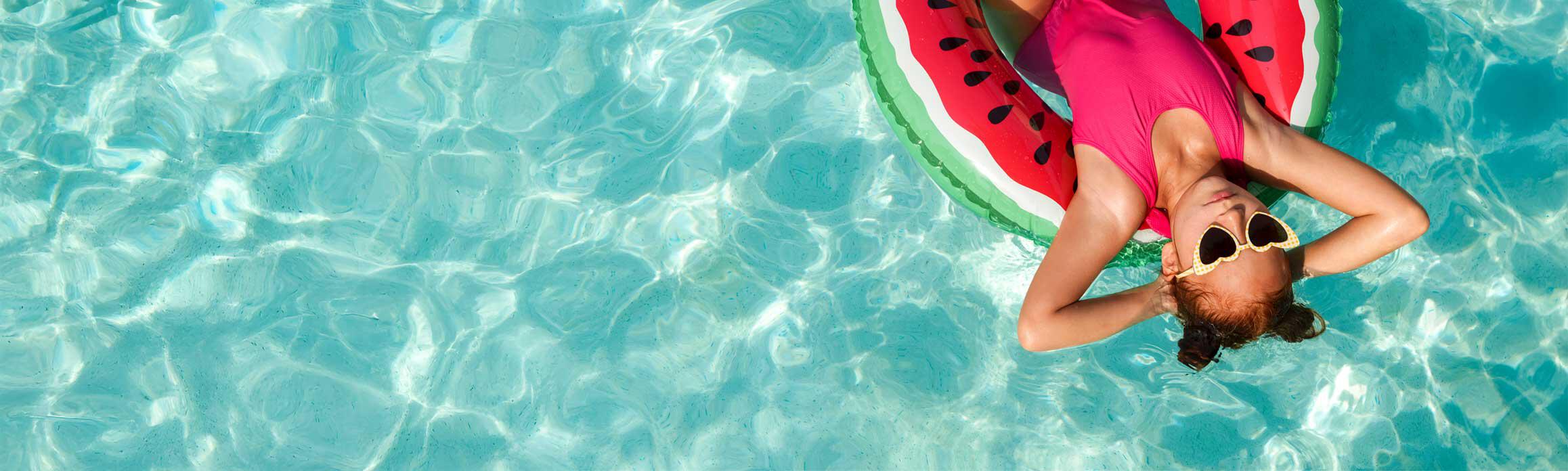 Girl on watermelon floatie in pool