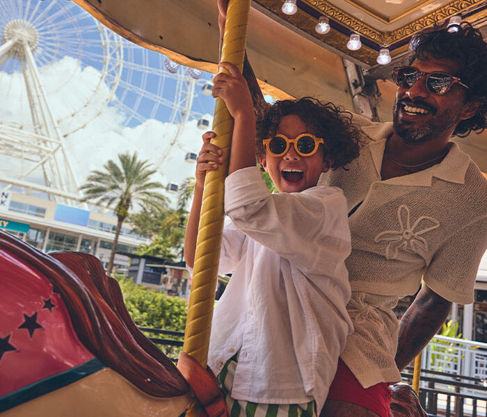 Fatehr and son on a carousel with the ICON wheel in the background
