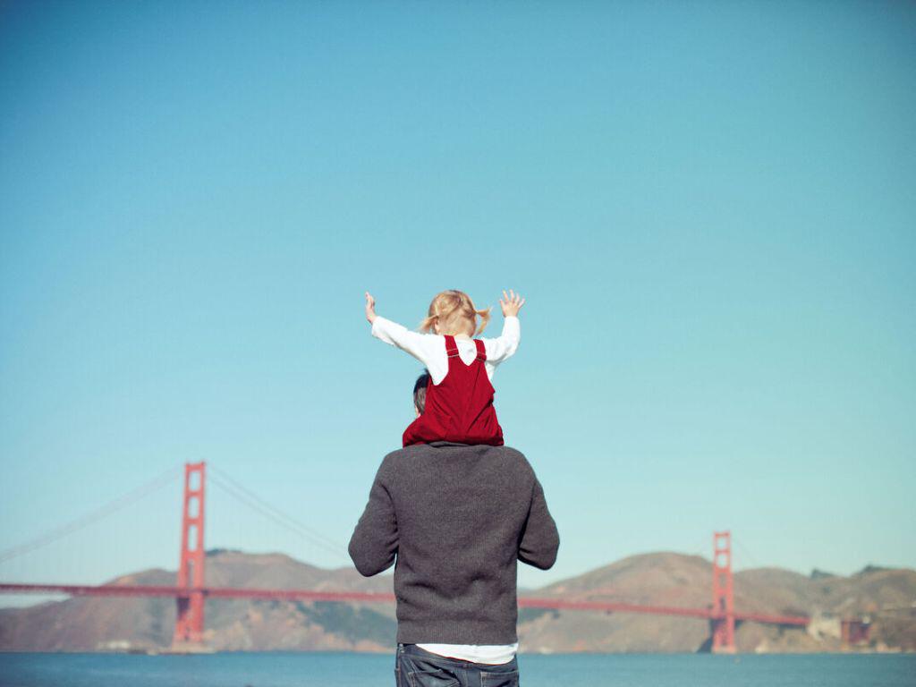 Girl on fathers shoulders by the Golden Gate bridge