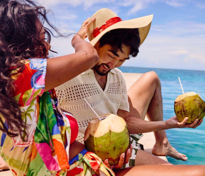 Couple by the sea with coconuts to drink from