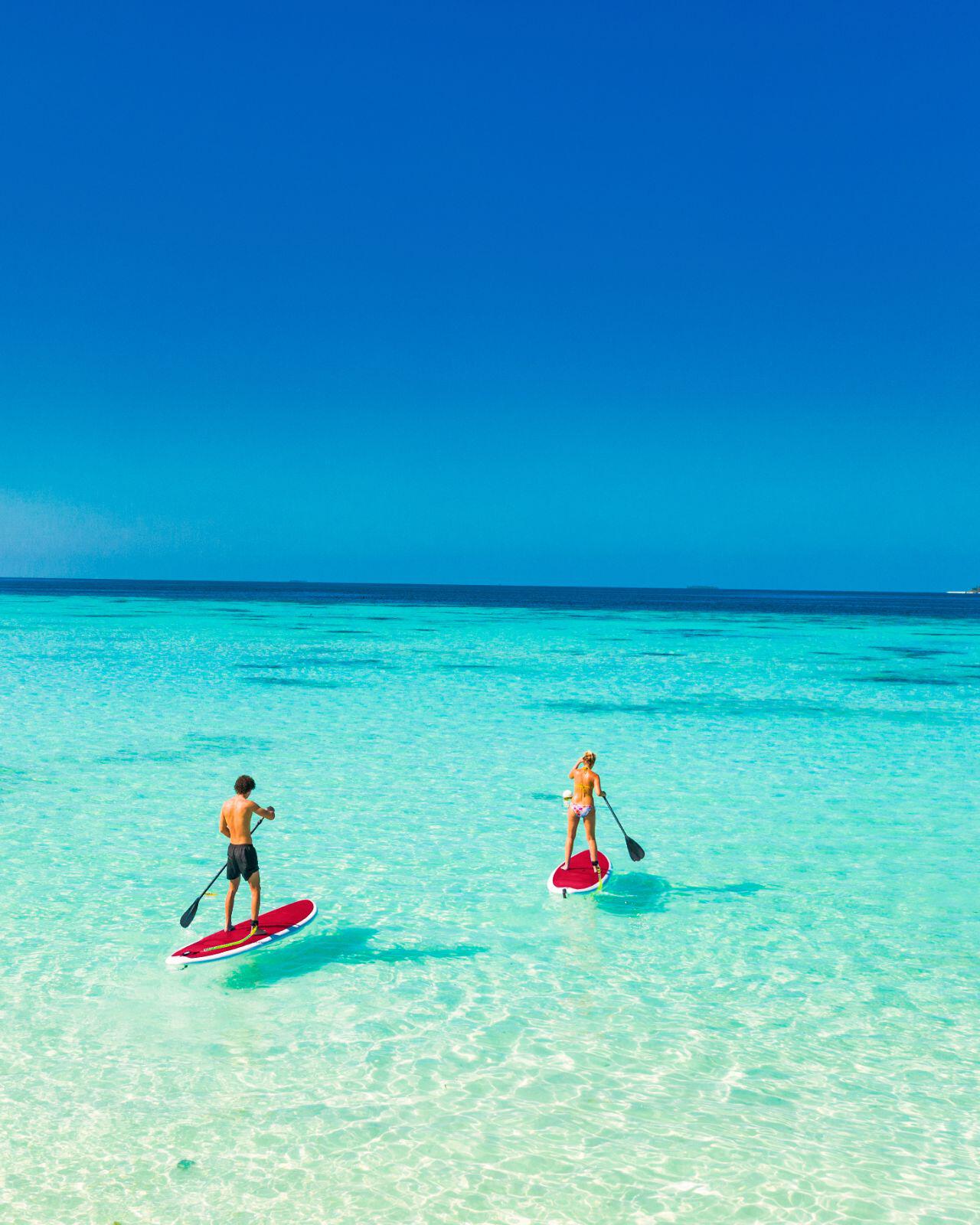 Couple paddle boarding in Maldives