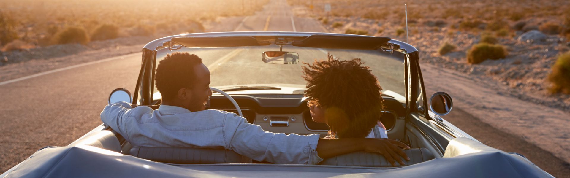 Couple driving with roof down on highway