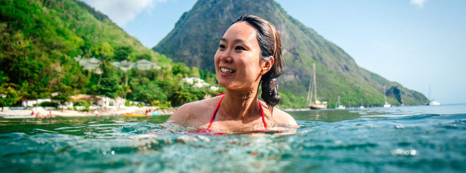 Lady swimming in the sea in St Lucia with with backdrop of the Pitons
