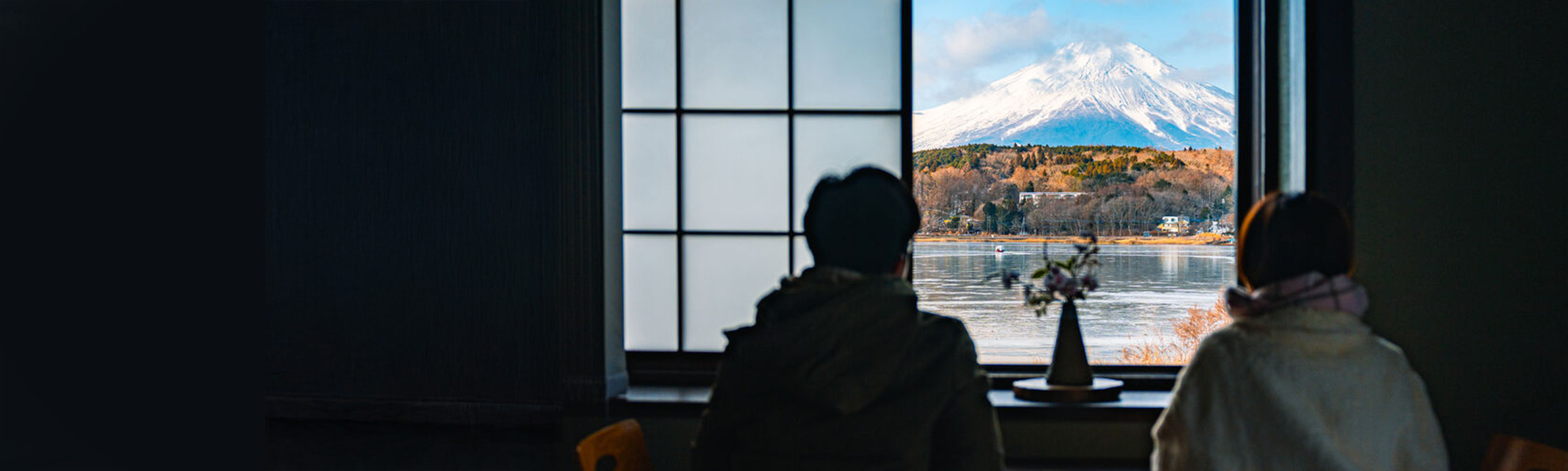 Two people look out of a window at a Mount Fuji on a clear day