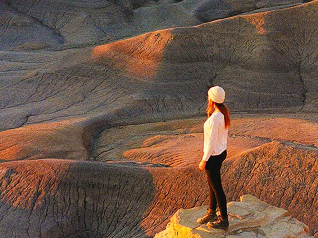 A woman stands on a rock in the centre of a red rock canyon