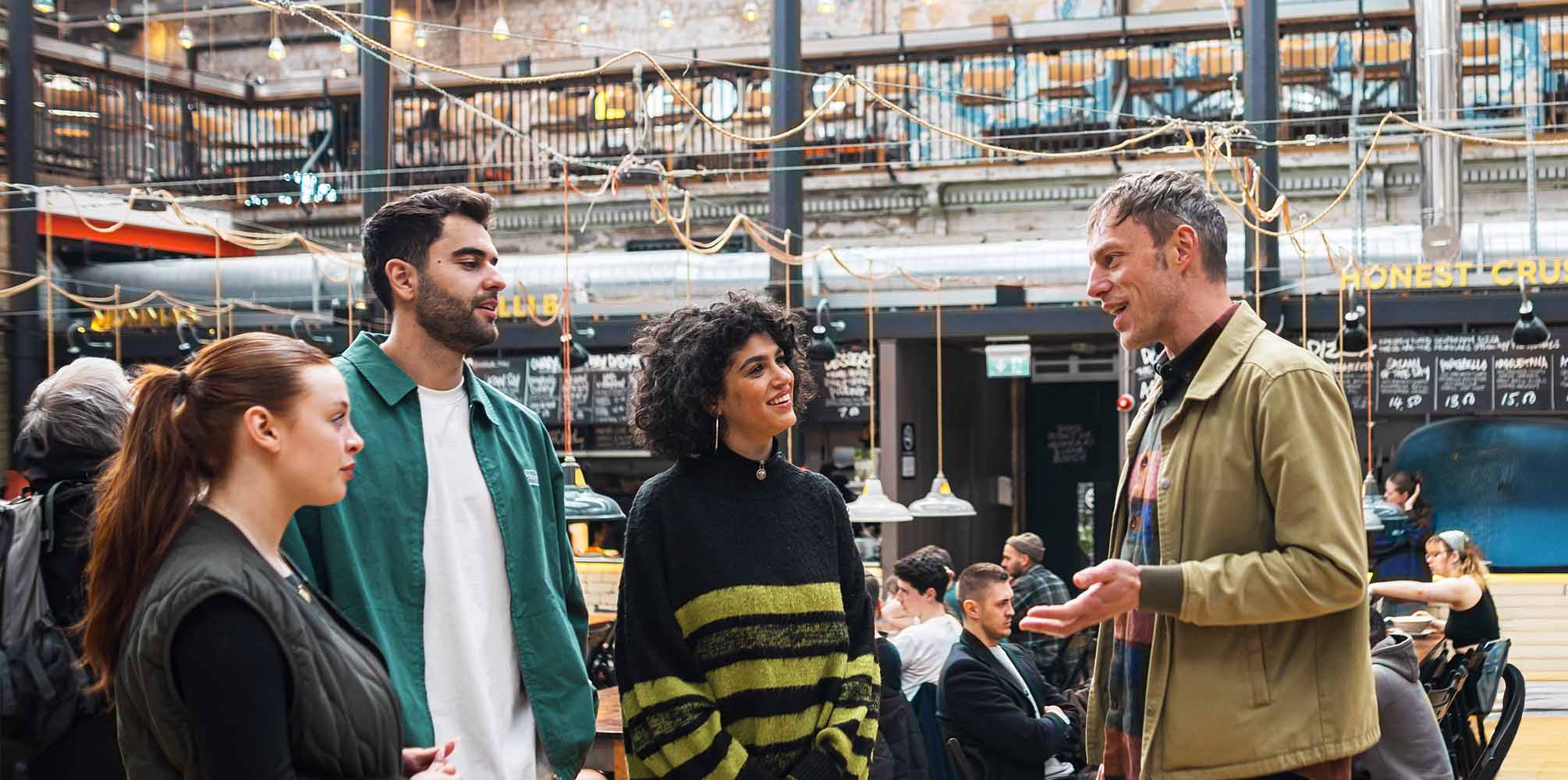 A tour talks to their group at a walking food tour inside a market in Manchester