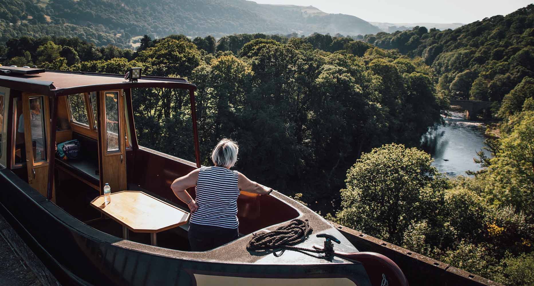 A woman looks out at a river from a boat