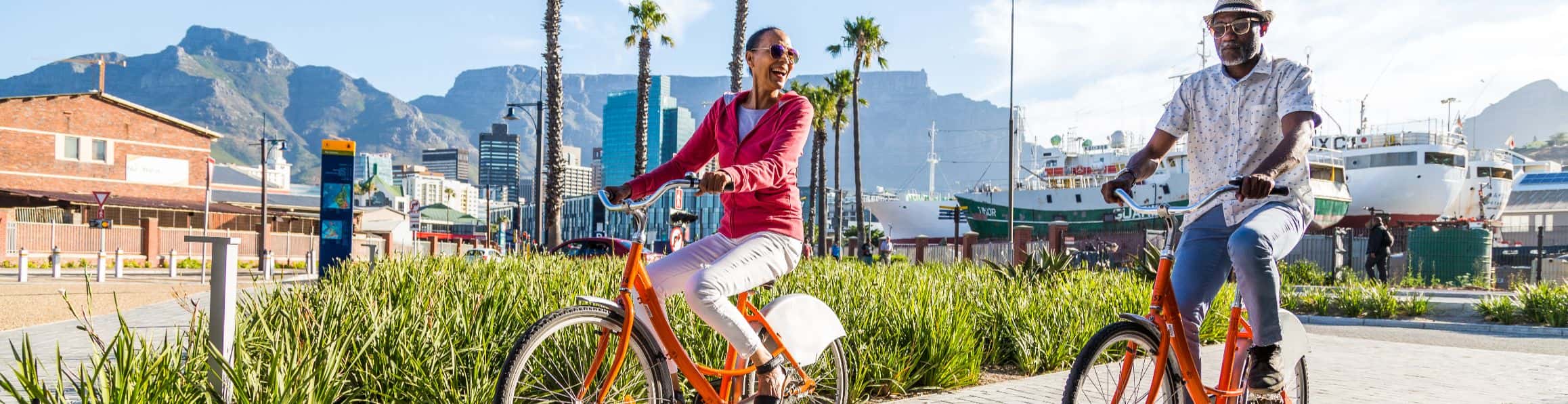 A couple cycling in Cape Town with the mountains in the background