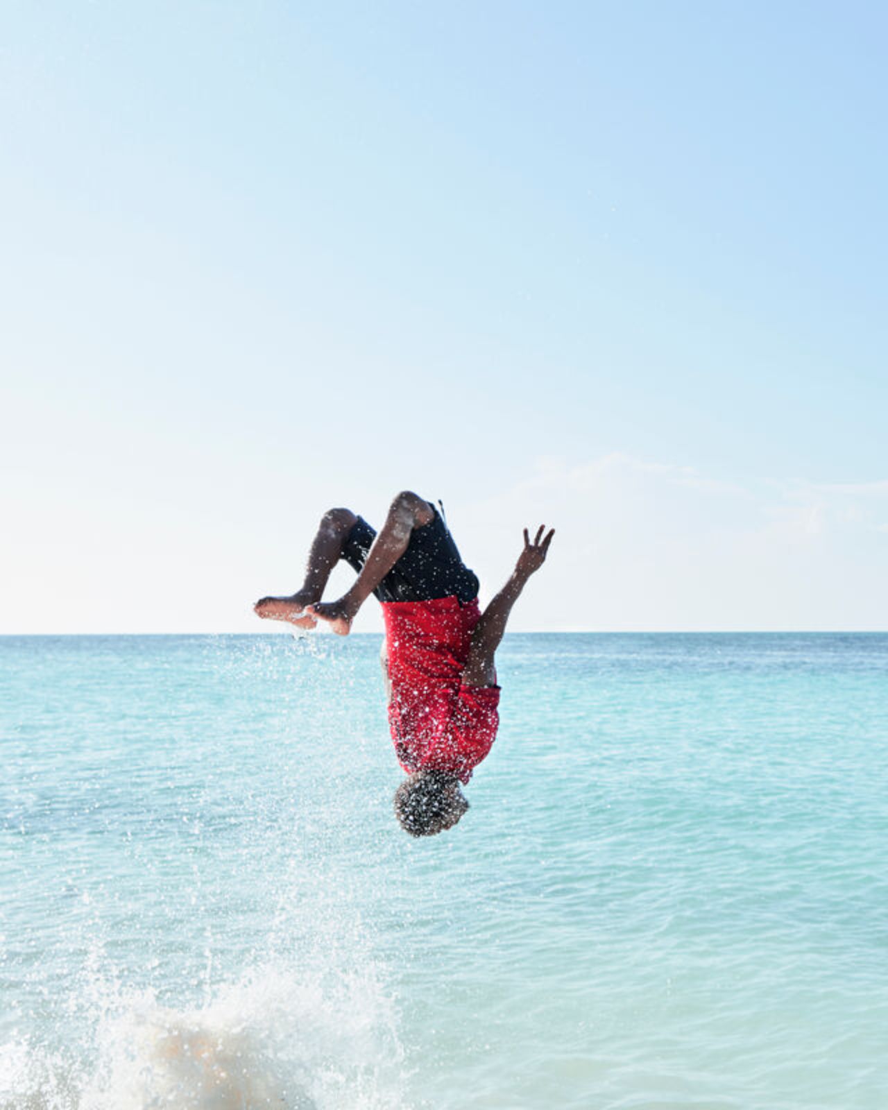 Man doing a backflip into the sea