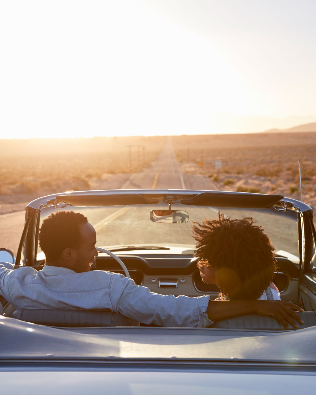 Couple driving with roof down on highway